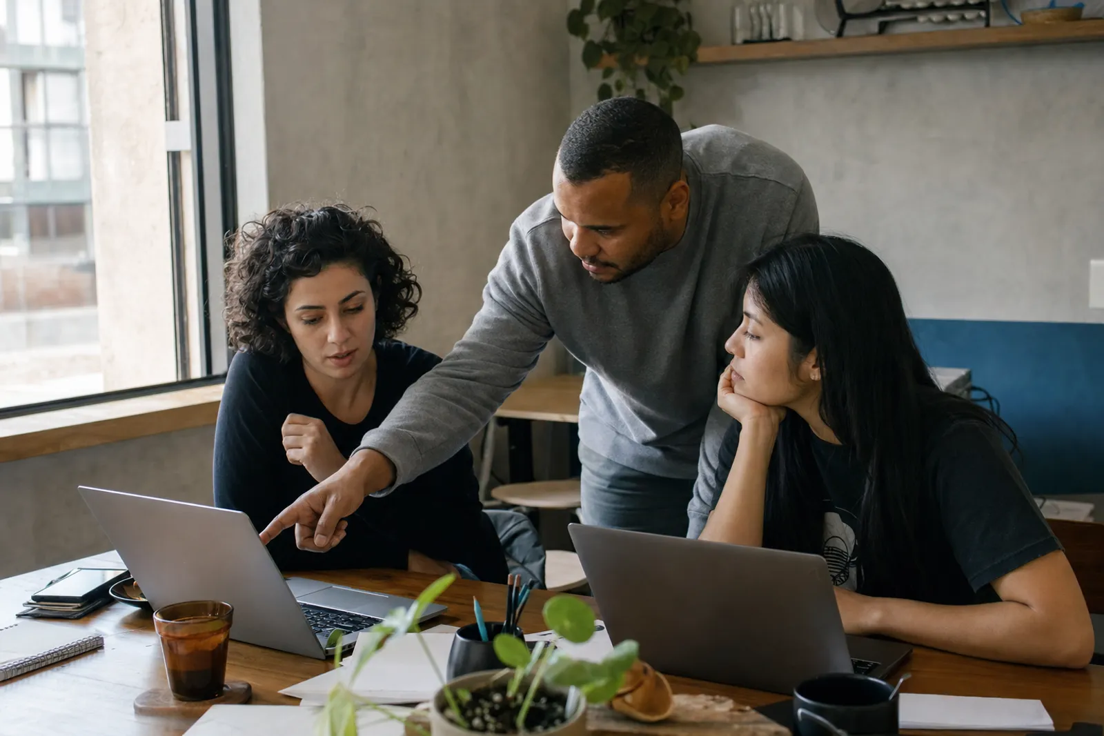 Equipe de agência revisando um projeto em conjunto na frente de dois notebooks
